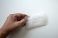 Hand holding a white package of disposable shower cap against white background Royalty Free Stock Photo