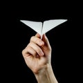 Hand holding a white paper airplane. Close up. Isolated on black background Royalty Free Stock Photo