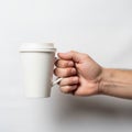 A hand holding a white paper coffee cup with a plastic lid. The background is plain white, emphasizi Royalty Free Stock Photo