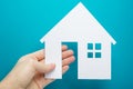 Hand holding white paper house figure on blue background. Real Estate Concept. Ecological building. Copy space top view. Royalty Free Stock Photo