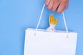 Hand holding a white paper shopping bag with white bunnies on a blue background. Shopping for Easter. Royalty Free Stock Photo