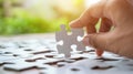 Hand holding a white puzzle piece above an incomplete jigsaw puzzle
