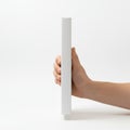 A hand holding a white rectangular object against a plain background Royalty Free Stock Photo