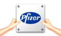 Hand holding a white signage of Pfizer for illustrative editorial use.