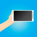 Hand holding white smart phone on blue background. Royalty Free Stock Photo