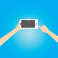 Hand holding white smart phone on blue background. Royalty Free Stock Photo