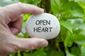 Hand holding a white stone with OPEN HEART text engraved on it, symbolizing life purpose of compassion and acceptance. Royalty Free Stock Photo