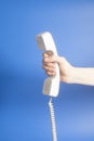 Hand holding white telephone tube on blue Royalty Free Stock Photo
