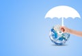 Hand holding white umbrella to protect blue planet earth. Royalty Free Stock Photo