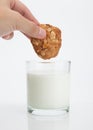 Hand holding whole grain cookies over fresh milk