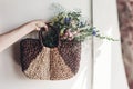 hand holding wildflowers in wicker bag at rustic window. colorful flowers in brown basket in sunlight, space for text. rural Royalty Free Stock Photo