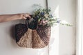 hand holding wildflowers in wicker bag at rustic window. colorful flowers in brown basket in sunlight, space for text. rural Royalty Free Stock Photo