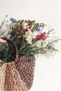 hand holding wildflowers in wicker bag at rustic window. colorful flowers in brown basket in sunlight, space for text. rural Royalty Free Stock Photo