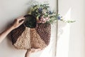 hand holding wildflowers in wicker bag at rustic window. colorful flowers in brown basket in sunlight, space for text. rural Royalty Free Stock Photo