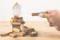 Hand holding wood block with model white house on wood block game. Investment risk and uncertainty in the real estate housing mark