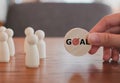 Hand holding wood blocks GOAL word with dart board symbols and different wooden figure person. Royalty Free Stock Photo