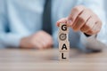 Hand holding wood wooden cubes with `goals` word on wooden tabletop, goal setting concept. challenge in business marketing as co