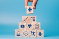 Hand holding wooden block cube which print screen health care and medical icons for healthy and wellness concept. Healthcare and