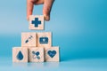 Hand holding wooden block cube which print screen health care and medical icons for healthy and wellness concept. Healthcare and