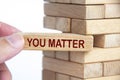 Hand holding a wooden block with text - You Matter to stabilize the entire wooden stacks. Inspirational and motivational