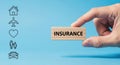 Hand is presenting a wooden block labeled insurance, with icons of home, travel, health, family, and auto coverage Royalty Free Stock Photo