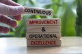 Hand holding wooden blocks with text - Continuous improvement and operational excellence. Royalty Free Stock Photo