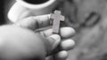 Hand holding wooden cross of Jesus Christ in black and white. Praying rosary concept. Christianity catholic symbol of faith