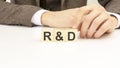 hand holding wooden cube blocks with text r and d - research and development - on white table background. marketing