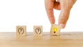 Hand holding wooden cube, bright lightbulb, on wood desk