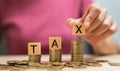 Hand holding wooden cubes with the word TAX on a pile of gold coins Royalty Free Stock Photo