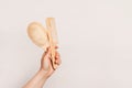 hand holding a wooden hairbrush and a wooden comb against a plain white background