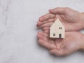Hand holding wooden house model on cement background, real estate, Real estate broker