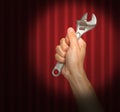 Hand holding a wrench under a spot light Royalty Free Stock Photo