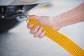 Hand holding yellow car towing strap with car