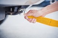 Hand holding yellow car towing strap with car