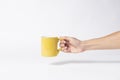 Hand holding Yellow ceramic coffee cup. mockup for creative design branding. white background Royalty Free Stock Photo
