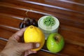 Hand holding yellow lemon, grapes and green apple isolated on wood background. Royalty Free Stock Photo