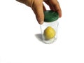 Hand holding yellow lemon inside an old glass jar. White background Royalty Free Stock Photo