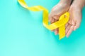 Hand holding Yellow ribbon on green background, copy space. Bone cancer Sarcoma Awareness childhood cancer cholangiocarcinoma Royalty Free Stock Photo