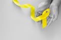 Hand holding Yellow ribbon on green background, copy space. Bone cancer Sarcoma Awareness childhood cancer cholangiocarcinoma Royalty Free Stock Photo