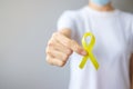 Hand holding Yellow Ribbon for supporting people living and illness. September Suicide prevention day, Childhood, Sarcoma and bone