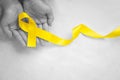 Hand holding Yellow ribbon on white background, copy space. Bone cancer, Sarcoma Awareness, childhood cancer, cholangiocarcinoma, Royalty Free Stock Photo