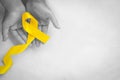 Hand holding Yellow ribbon on white background, copy space. Bone cancer, Sarcoma Awareness, childhood cancer, cholangiocarcinoma, Royalty Free Stock Photo