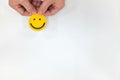 Hand holding a yellow smiley face on a white background. Happy customer, positive feedback and good service concepts Royalty Free Stock Photo