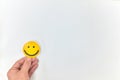 A hand holding a yellow smiley face on a white background. Happy customer, positive feedback and good service concepts Royalty Free Stock Photo