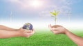 Hand holding young plant and earth globe on wind turbine with blue sky background. Royalty Free Stock Photo