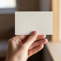 A hand holds a blank, rectangular card against a blurred indoor backdrop. The card appears to be Royalty Free Stock Photo