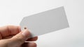 Hand holds a blank, white rectangular tag with a diagonal cut on Royalty Free Stock Photo