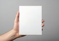 Hand holding a blank white square object against a gray background {Ai generated Royalty Free Stock Photo