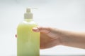 Hand holds a bottle with yellow liquid soap and dispenser standing on a table on a white background. Horizontal orientation Royalty Free Stock Photo